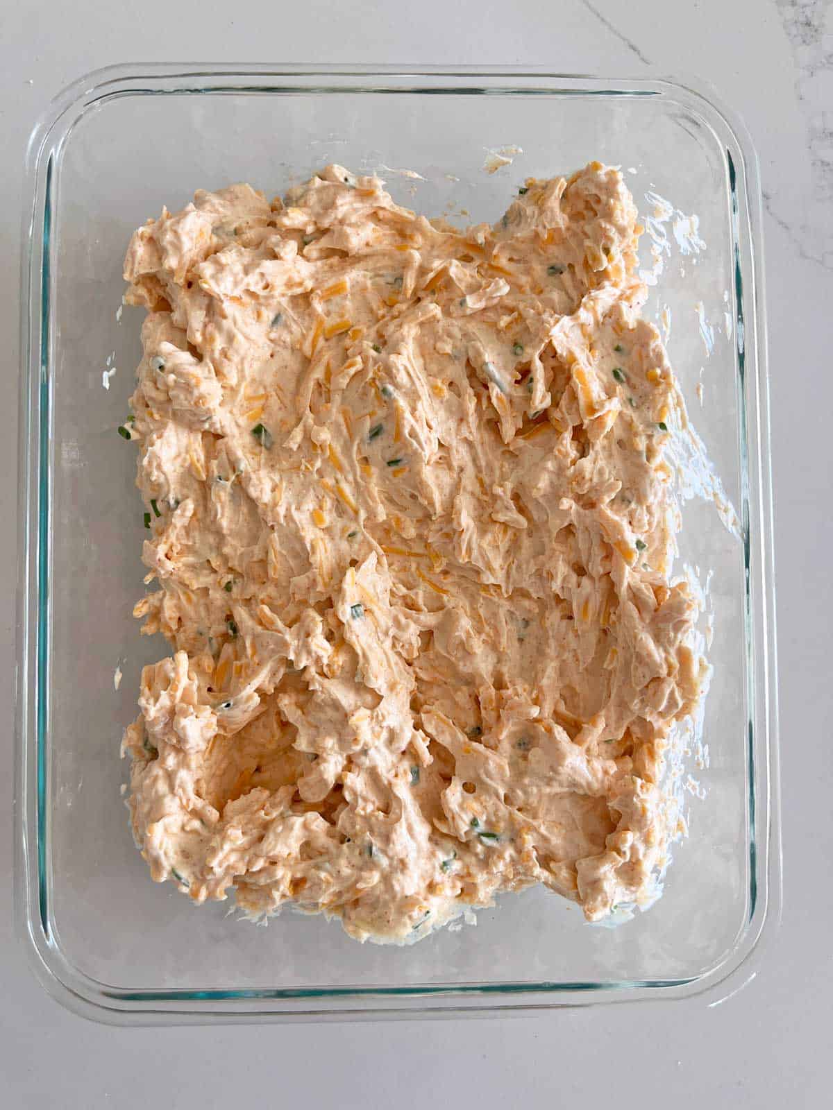 Leftovers of cream cheese dip are stored in a glass food storage container.