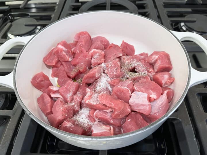Adding cubed pork tenderloin, salt, and pepper to the saucepan.