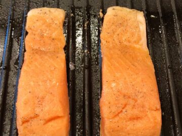 Two salmon fillets are placed on the grill.