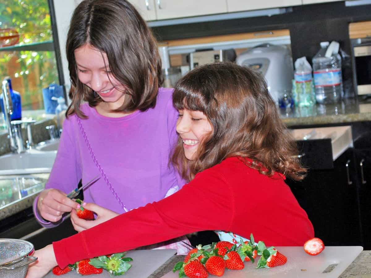 Vered's young daughters making chocolate-covered strawberries.