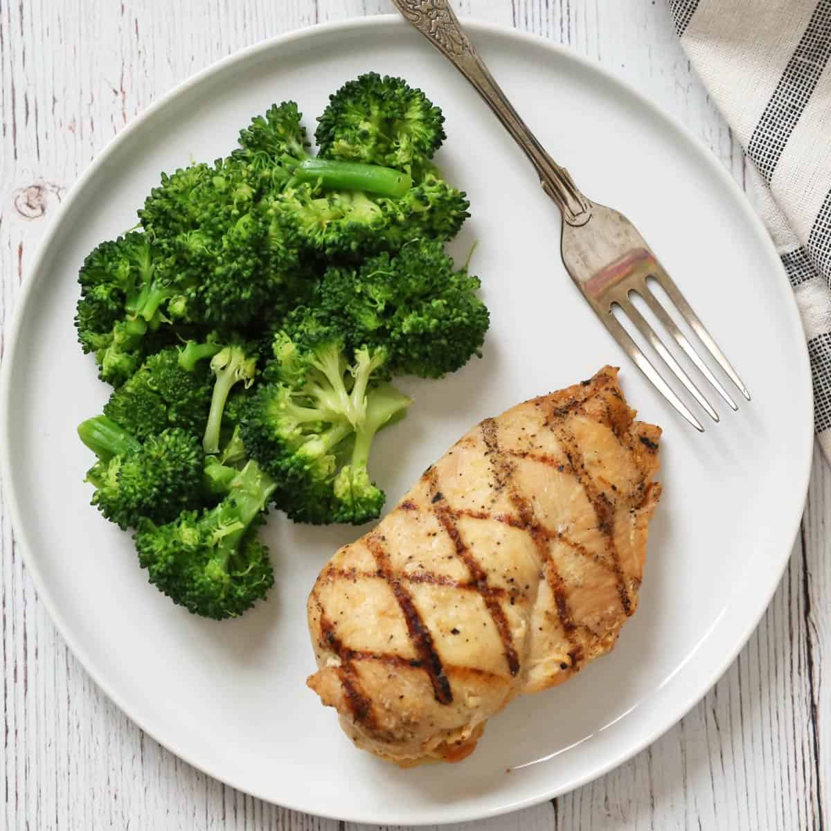 Microwave broccoli is served with grilled chicken breast.