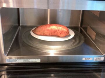 Placing the sweet potato in the microwave.