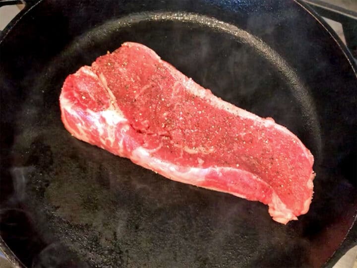 Placing the steak in the skillet.
