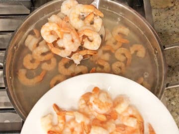 Removing the shrimp from the water with a slotted spoon.