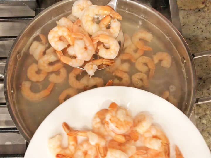 Removing the shrimp from the water with a slotted spoon.