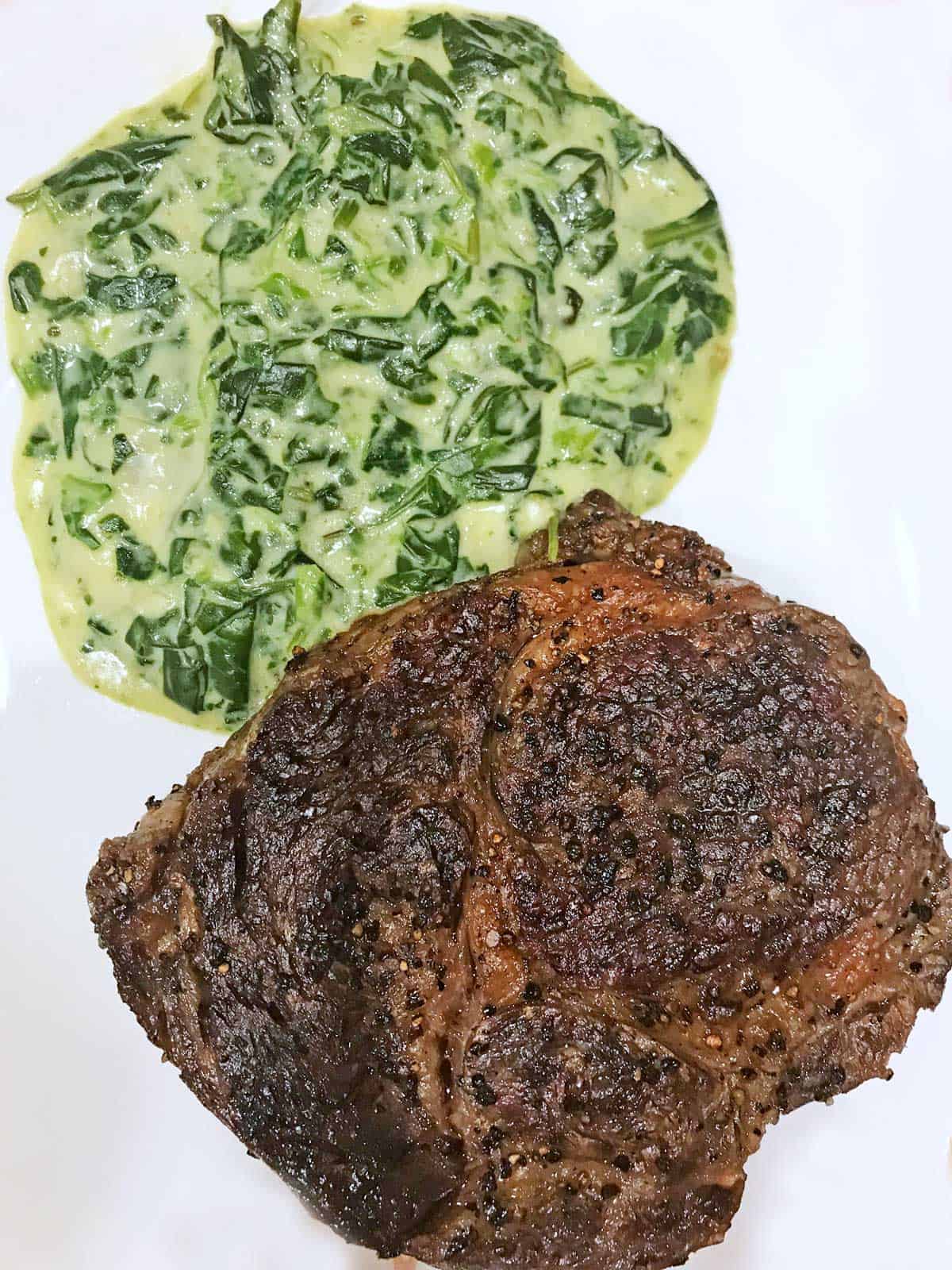 A restaurant ribeye and creamed spinach.