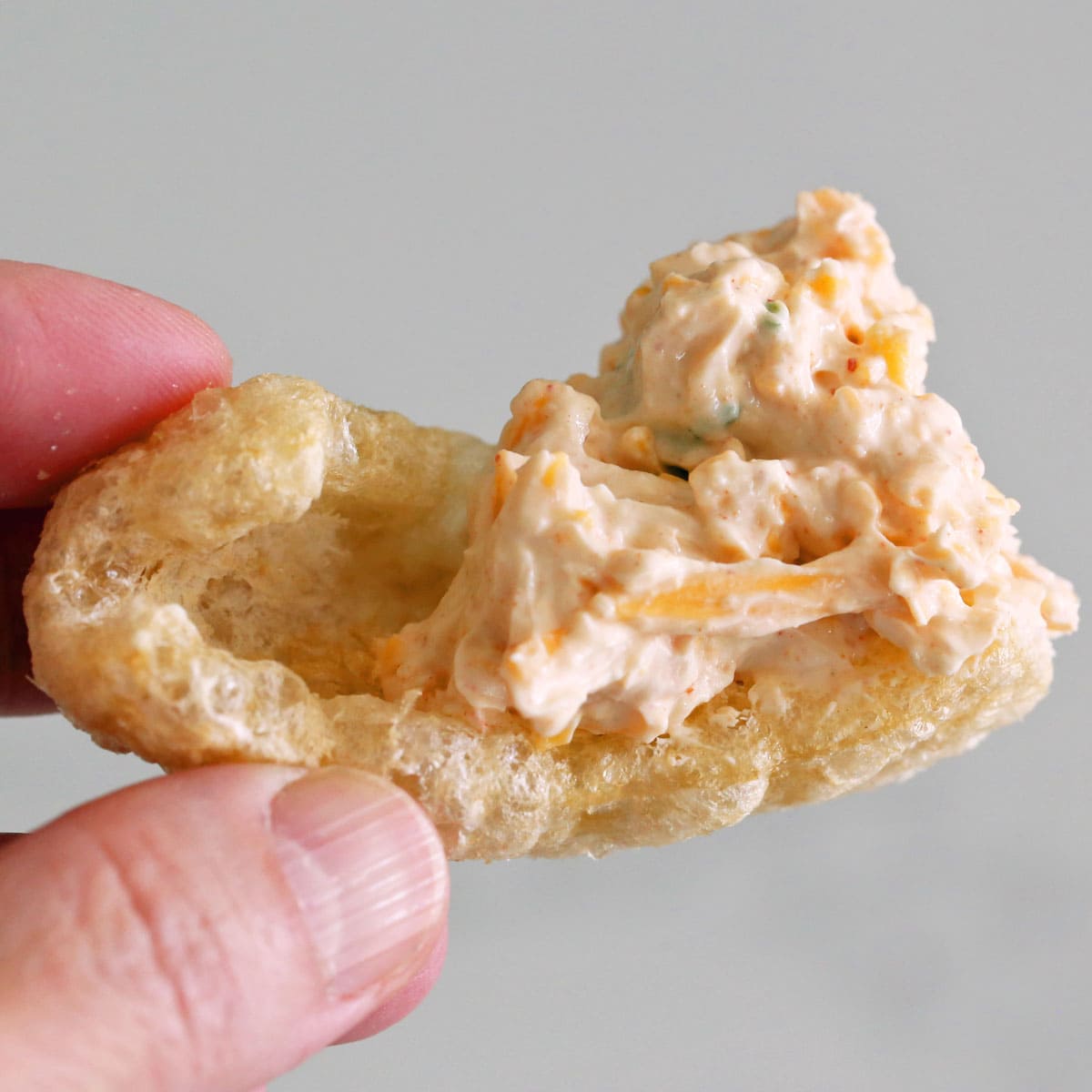 Scooping cream cheese dip with pork rinds.