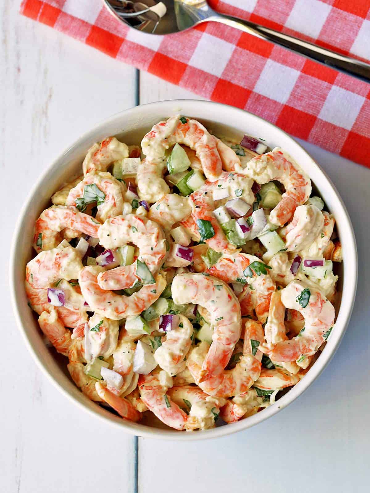 Shrimp salad is served in a white bowl.