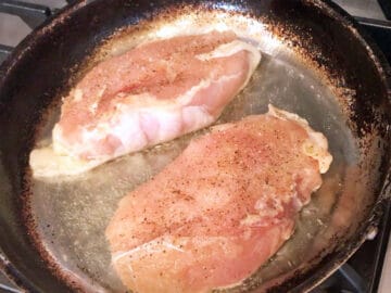 Placing the chicken in the skillet, skin side down.