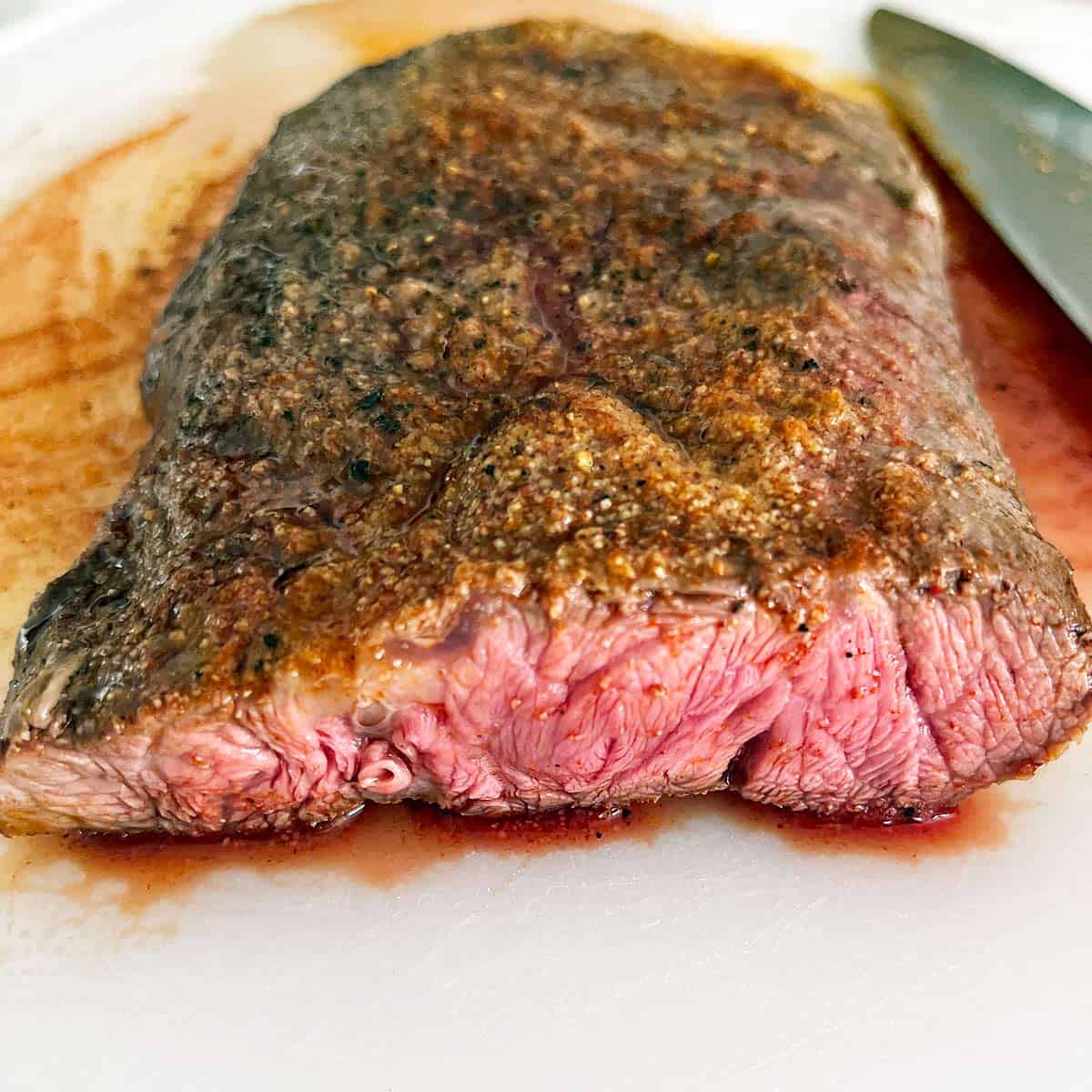 Slicing a flat iron steak on a cutting board.