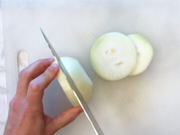 Slicing an onion on a cutting board.