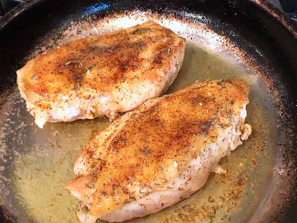 Butter sauce was spooned on top of the chicken pieces in the skillet.