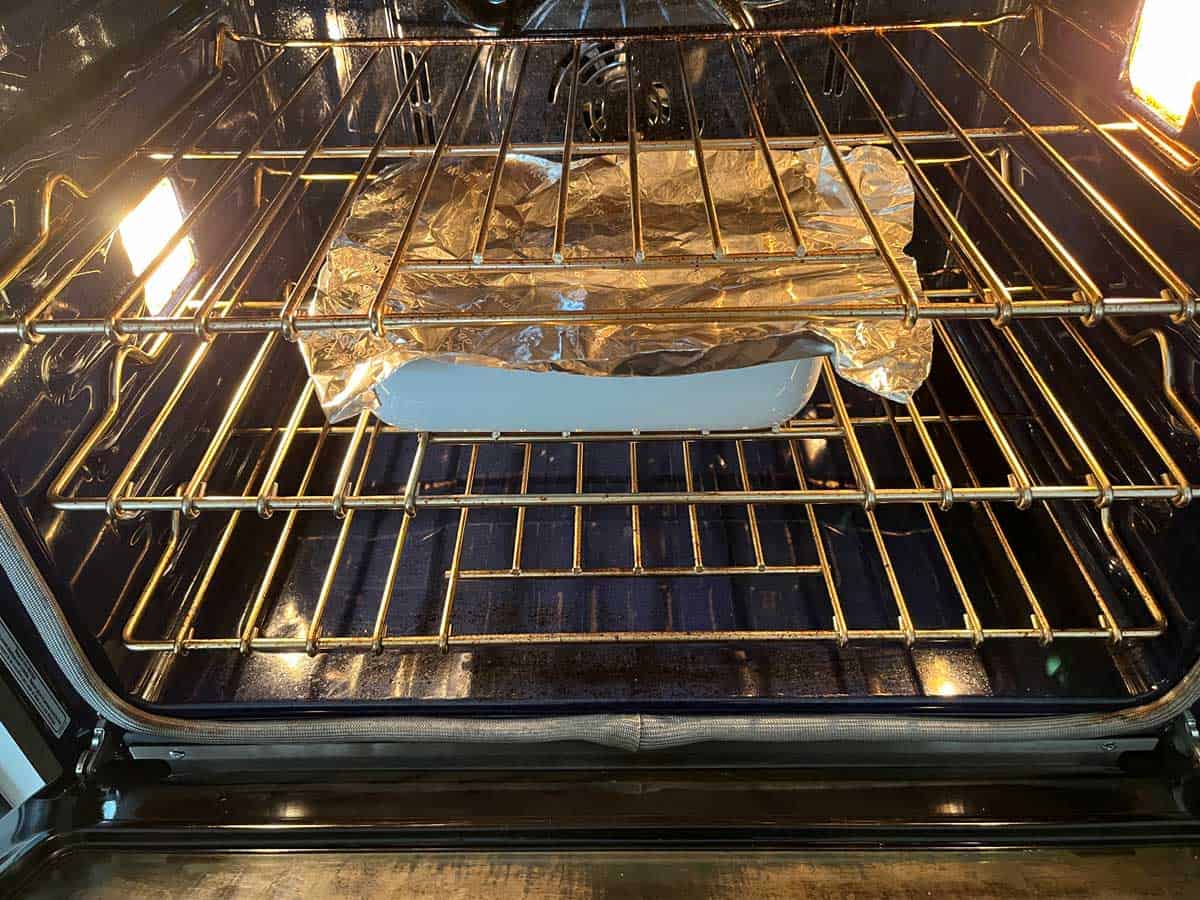 A baking dish tented with foil in the oven.