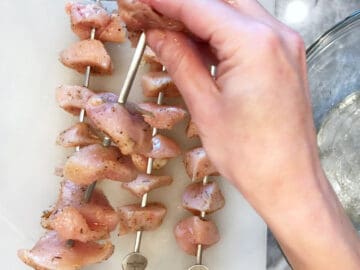Threading the seasoned chicken cubes on skewers.