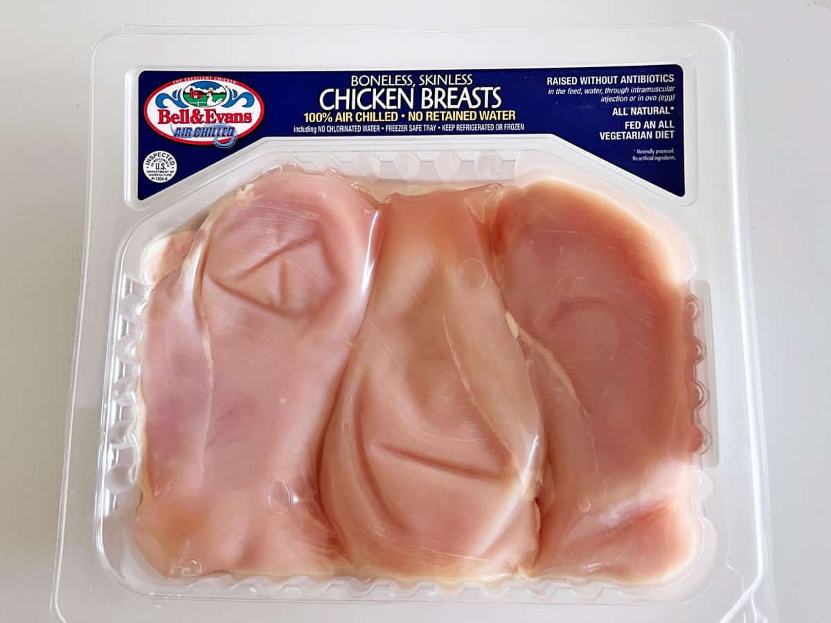 A package of three raw chicken breasts.