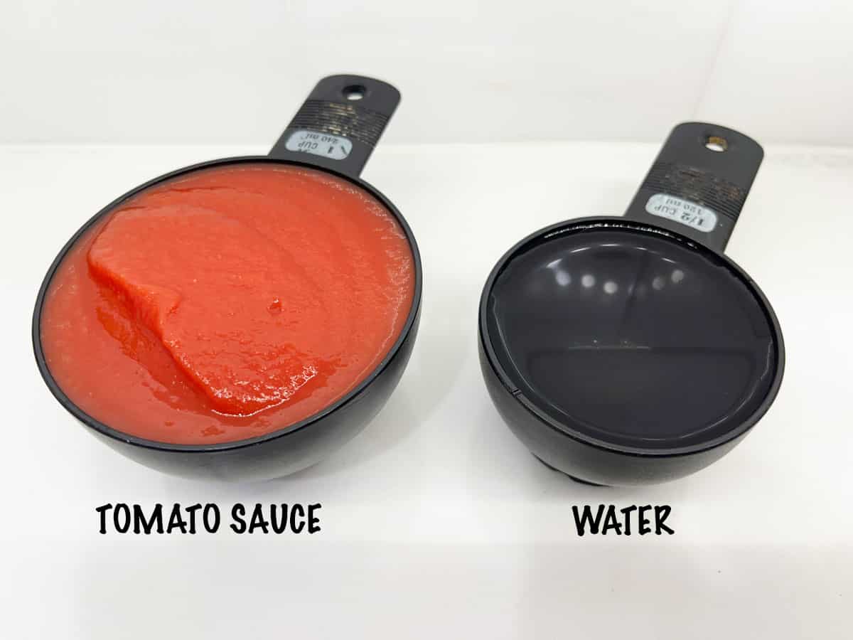 Measuring cups with tomato sauce and water.