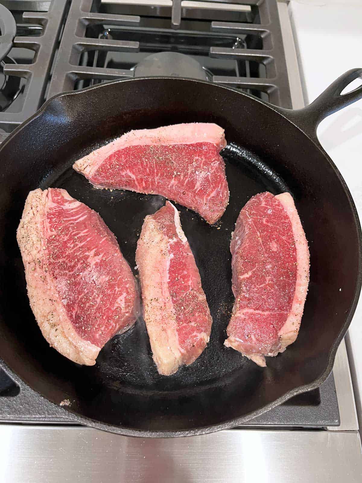 Different sizes of picanha are cooked in the same skillet.