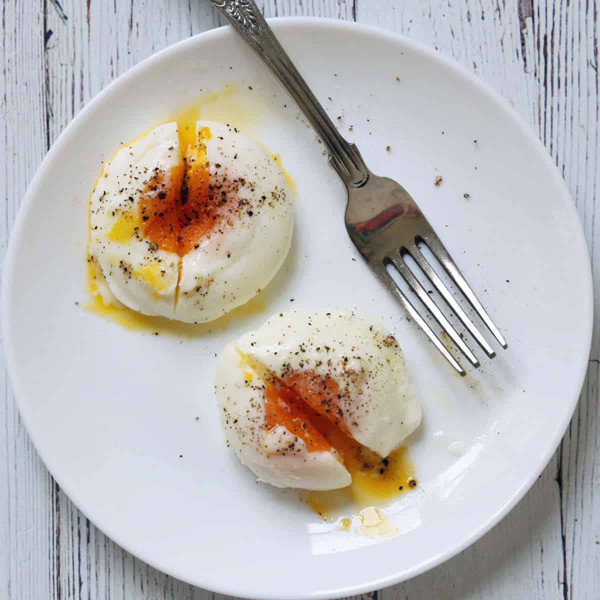 Two microwave-poached eggs on a plate.