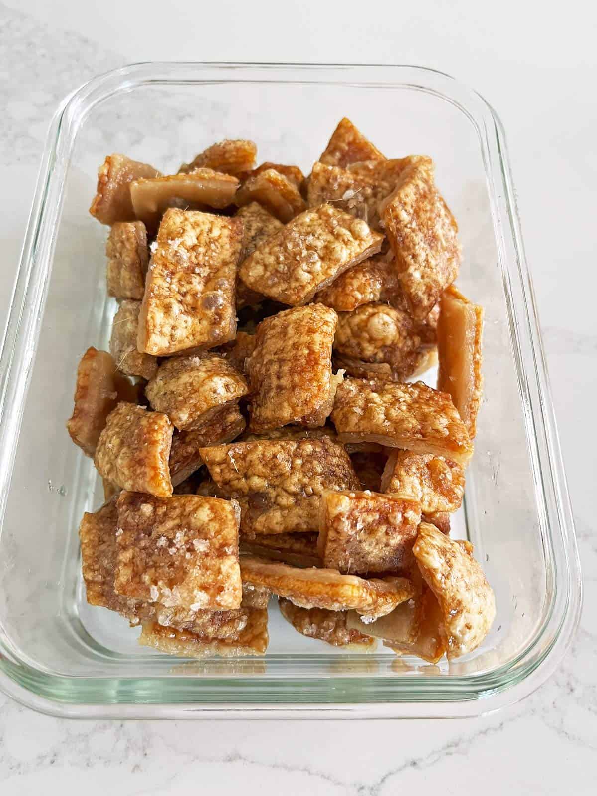 Storing pork rinds in a glass food storage container.
