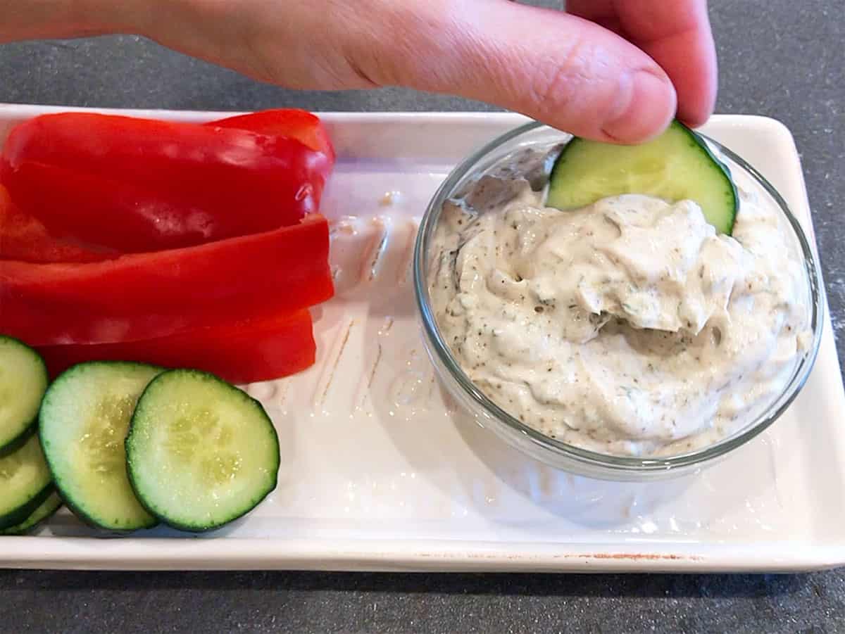 Scooping the yogurt dip with a slice of cucumber.