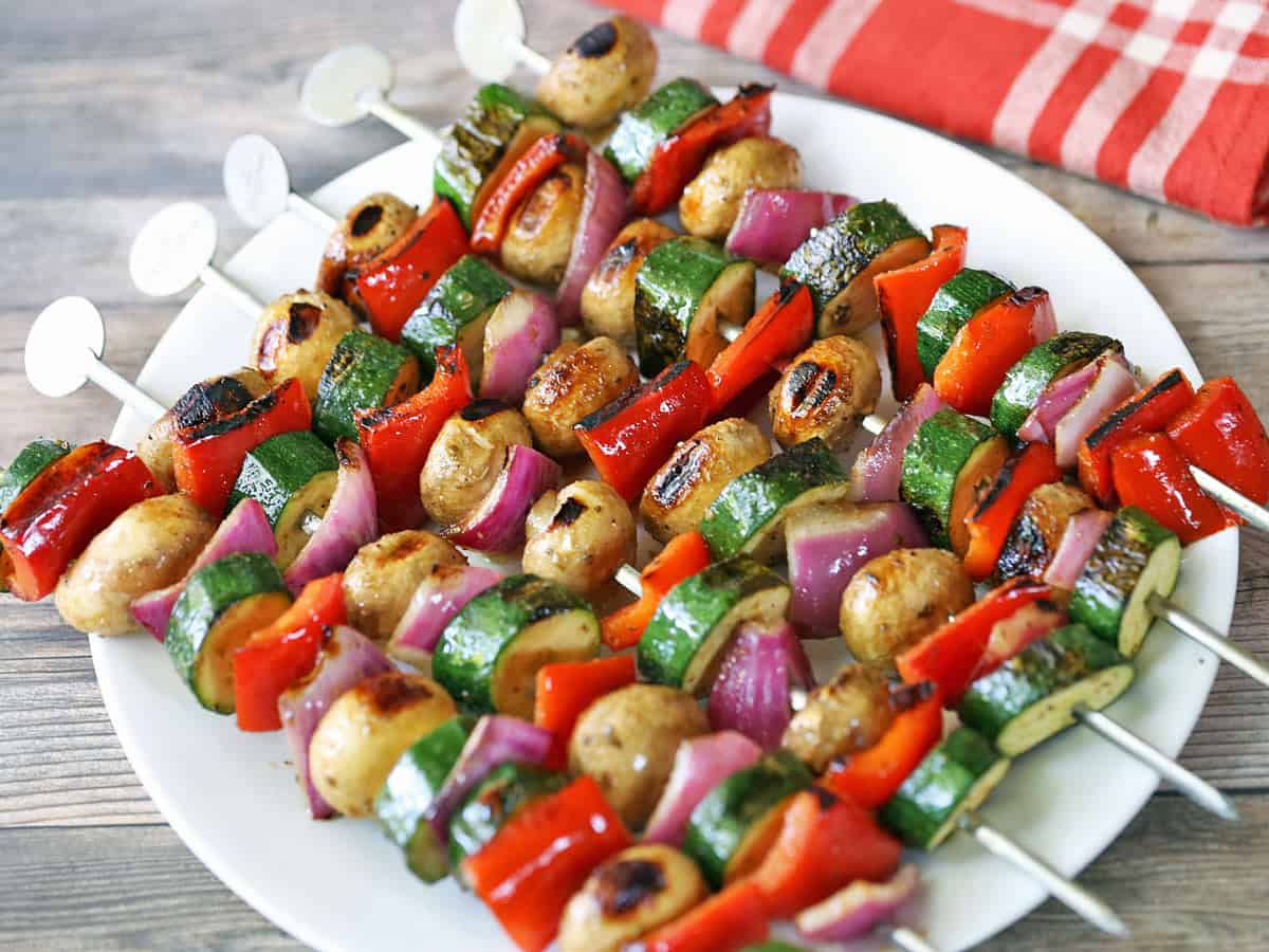 Veggie kabobs are served on a white plate.