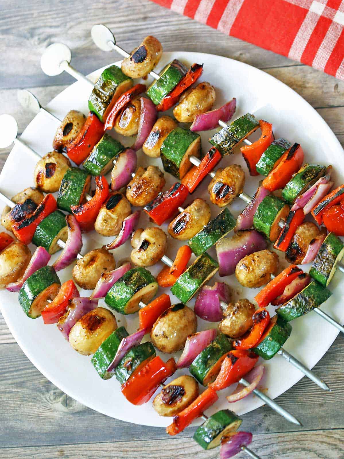 Vegetable kabobs are served on a white plate.