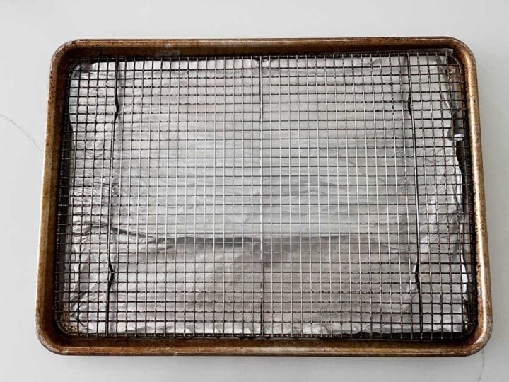 A baking sheet is lined with foil and fitted with a wire rack.