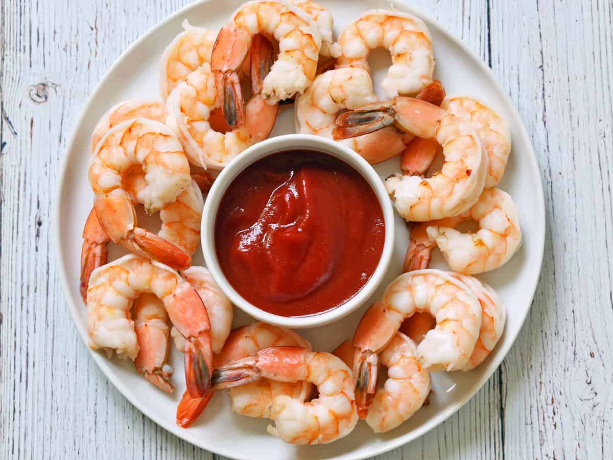 Boiled shrimp are served with cocktail sauce.
