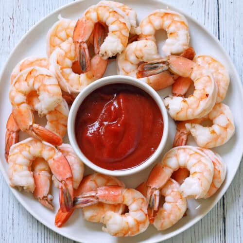 Boiled shrimp are served with cocktail sauce.