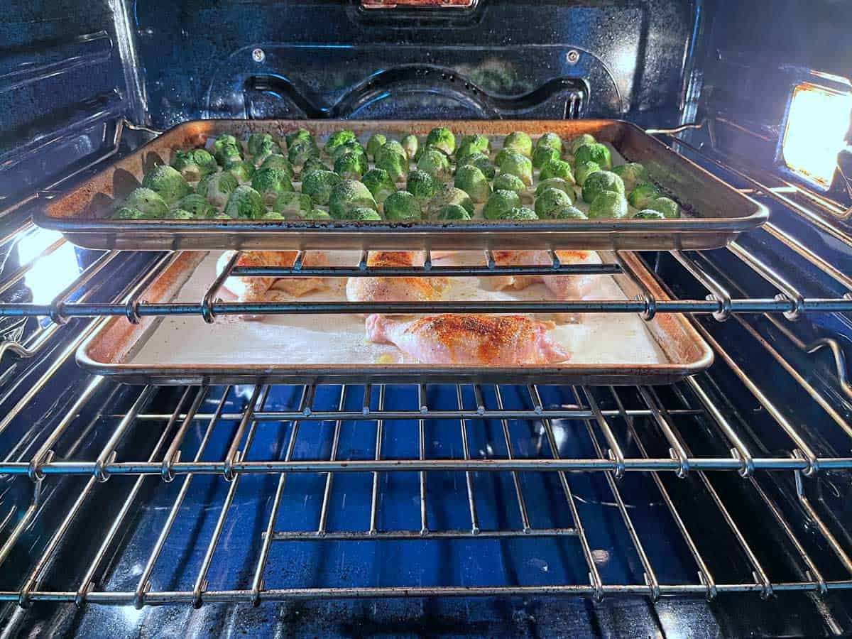Chicken quarters and Brussels sprouts are baked together in the oven.