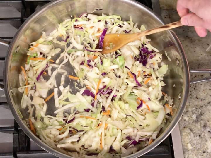 Cooking shredded cabbage, garlic, and ginger in a skillet.