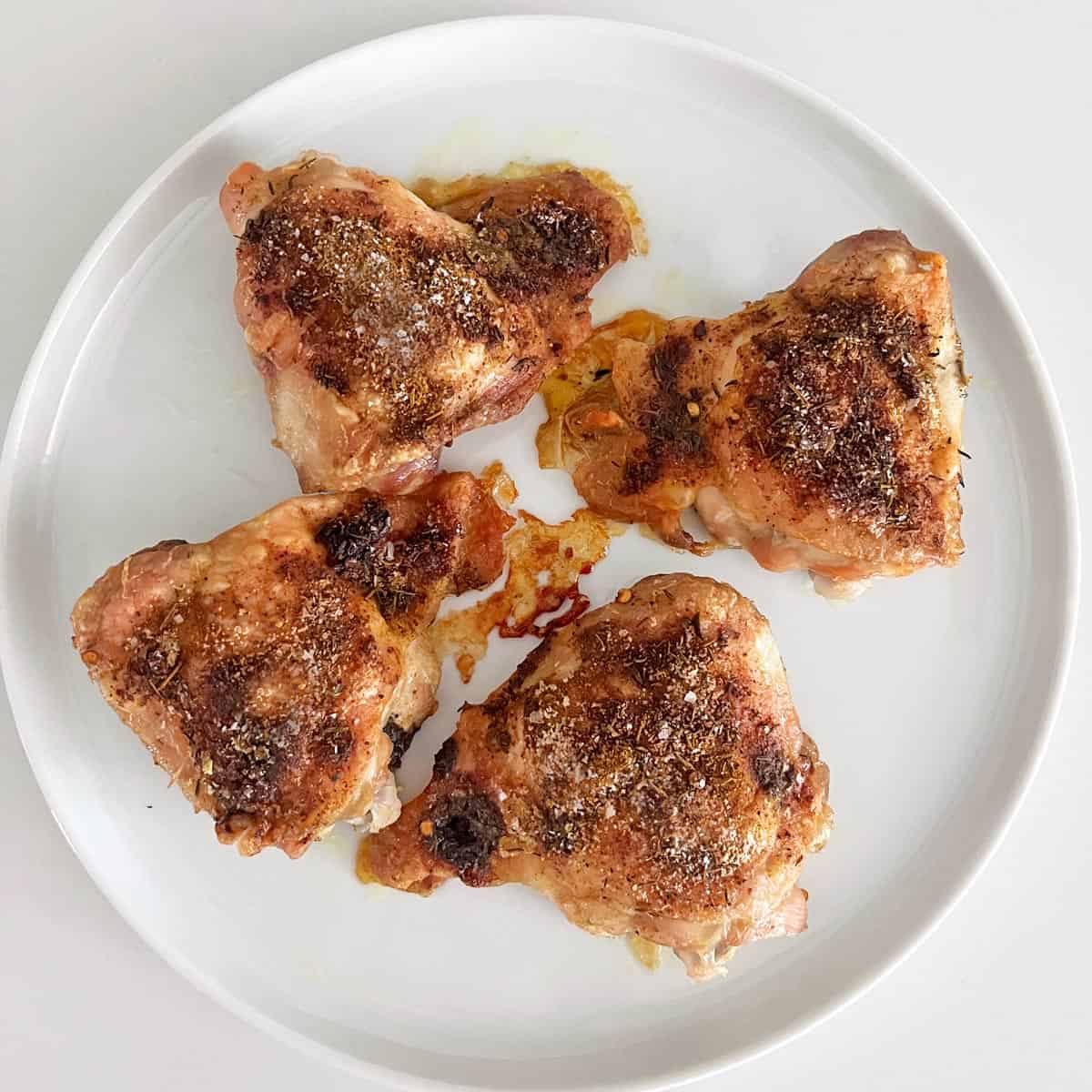 Jerk chicken thighs are served on a white plate.