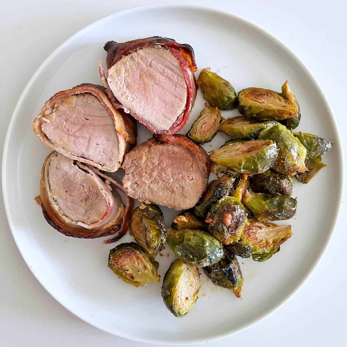 Bacon-wrapped pork tenderloin leftovers are served with reheated Brussels sprouts.