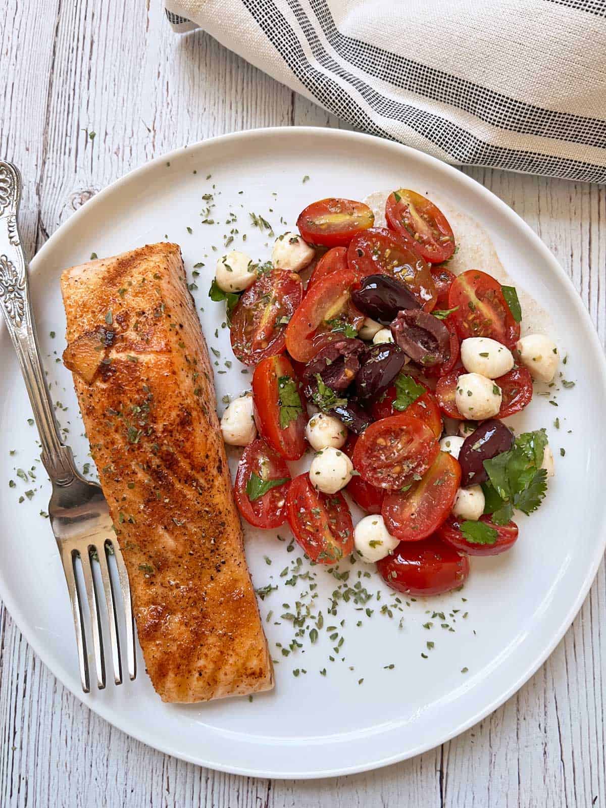 Pan-seared salmon is served with tomato salad.