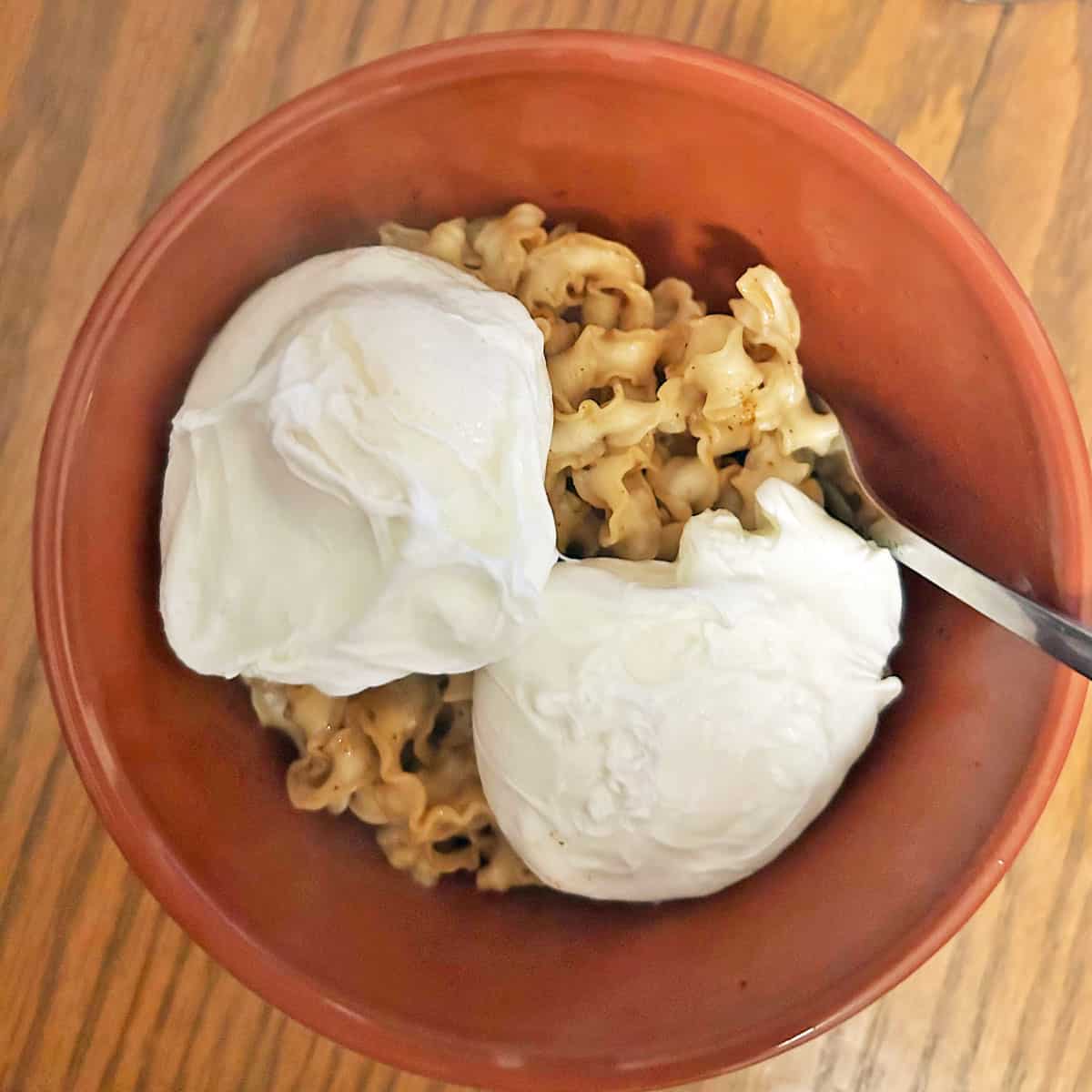 Two poached eggs on top of noodles in a bowl.