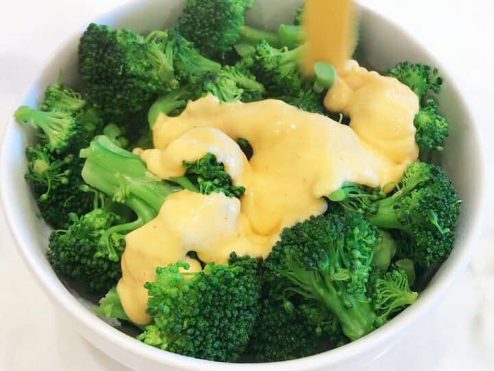 Pouring the cheese on the broccoli.