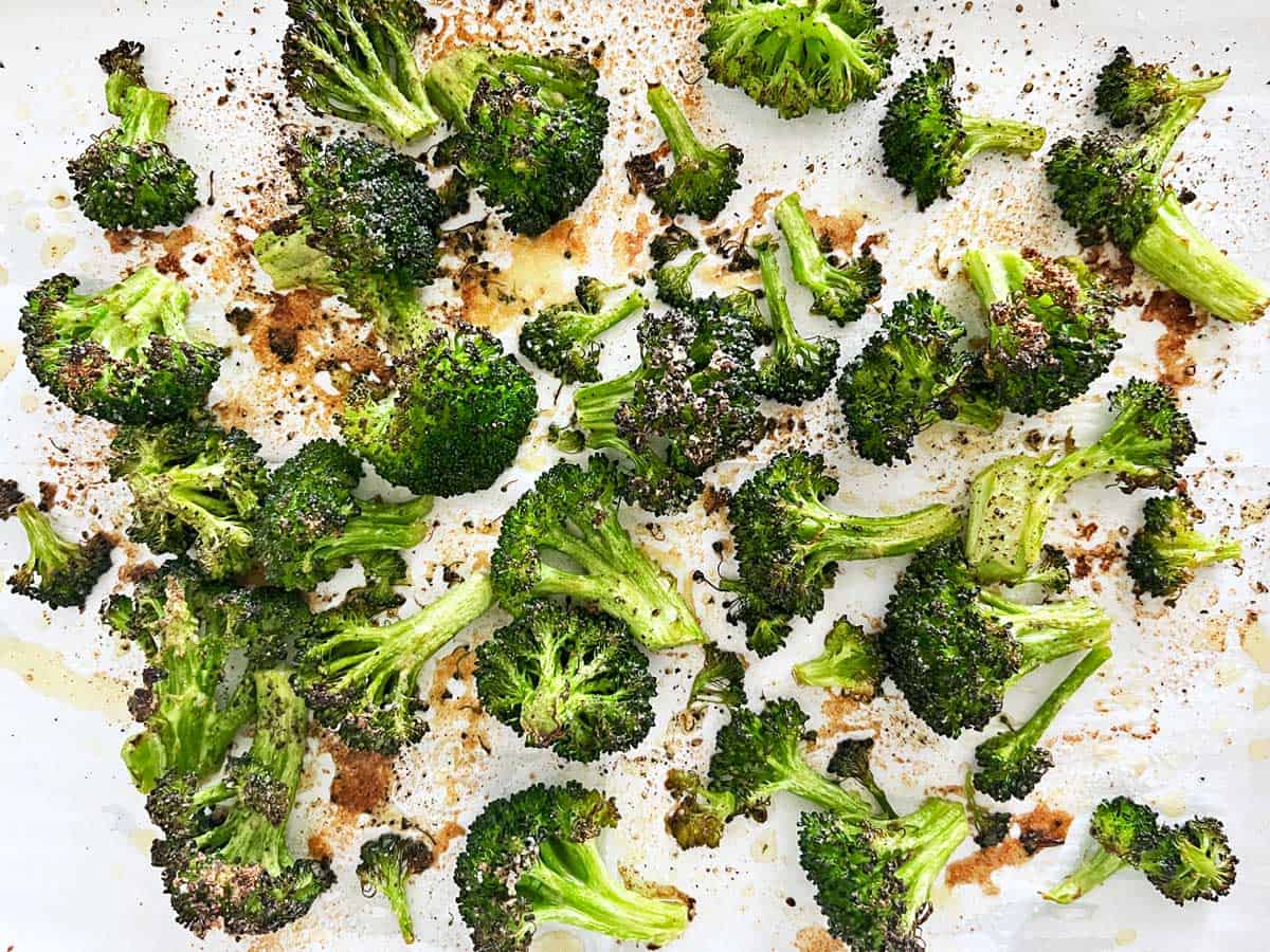 Roasted broccoli on a parchment-lined baking sheet.