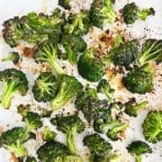 Oven-roasted broccoli on a parchment-lined baking sheet.
