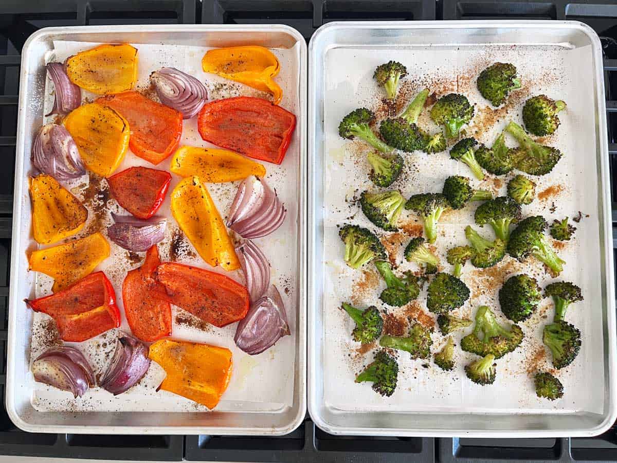 A sheet pan with roasted broccoli and another one with roasted peppers and onions.
