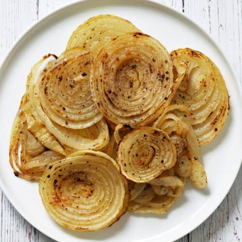 Roasted onions are served on a white plate.
