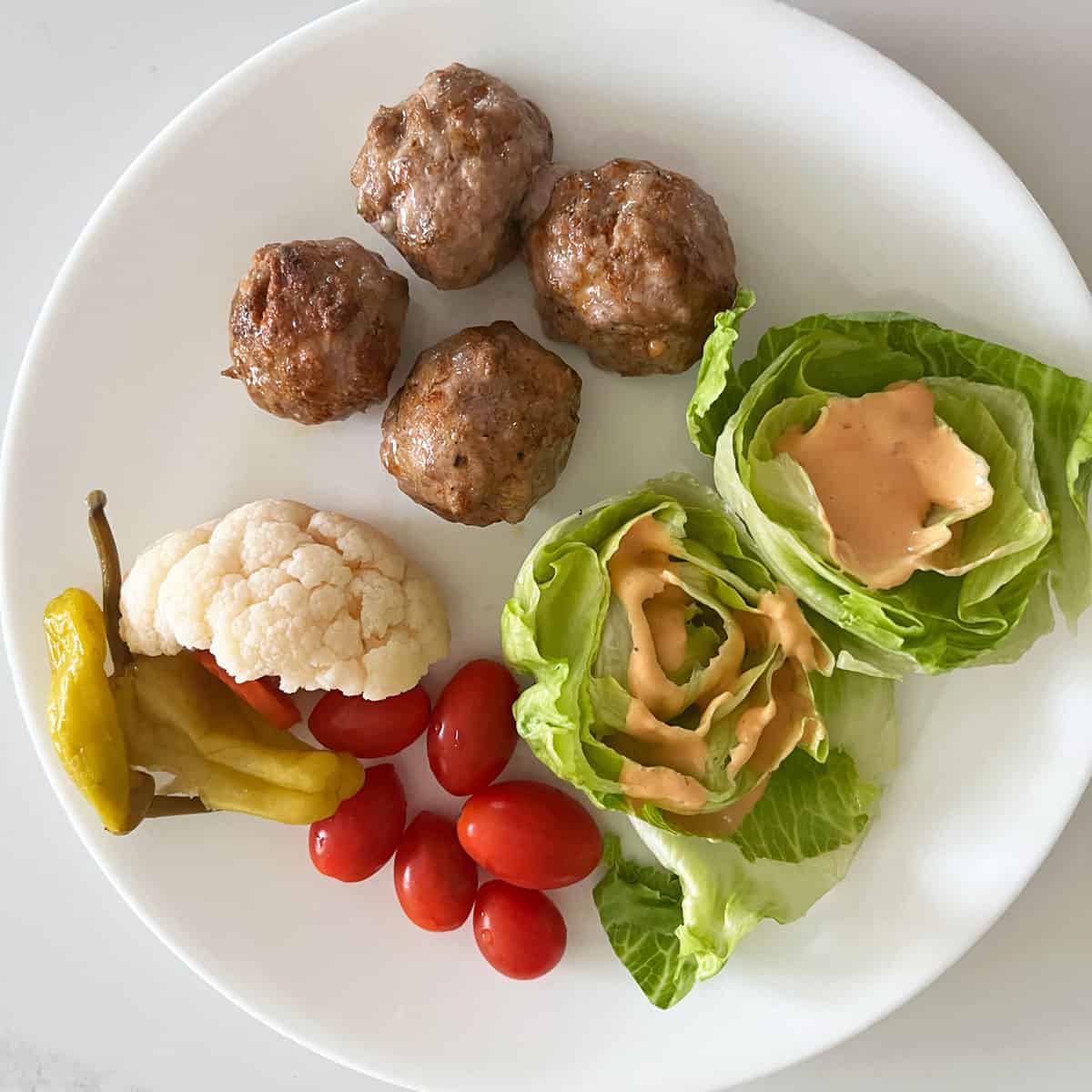 The meatballs are served with veggies and pickles.