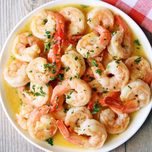 Shrimp scampi is served on a white plate with a napkin.