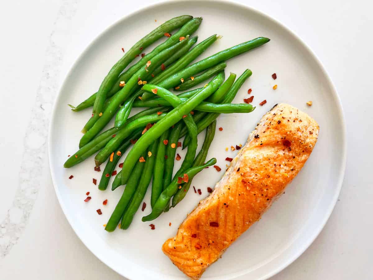 Boiled green beans are served with salmon.