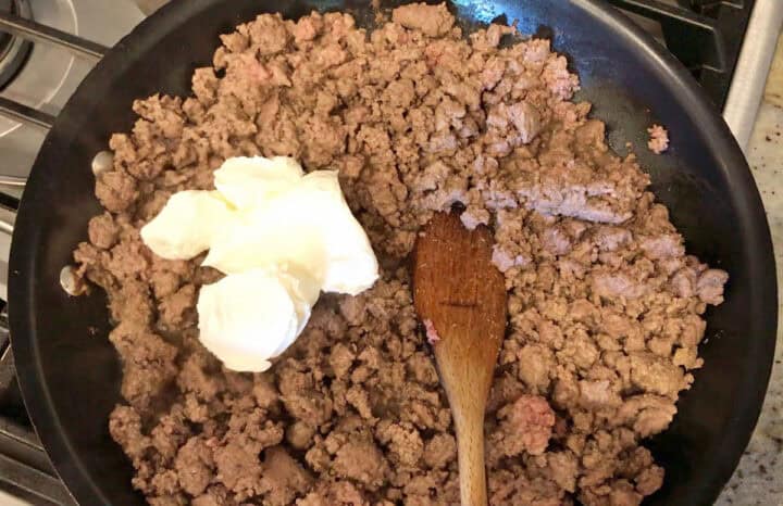 Mixing cream cheese into the ground beef.