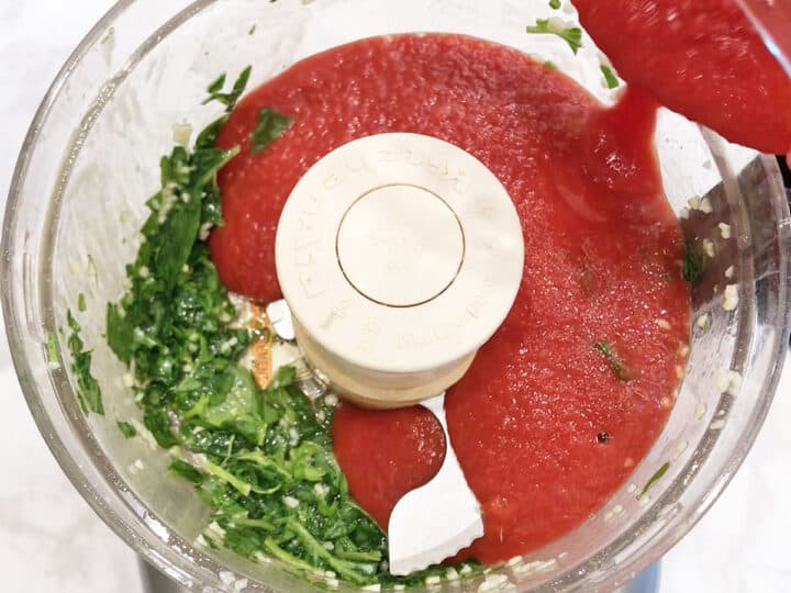 Adding strained tomatoes to the food processor.