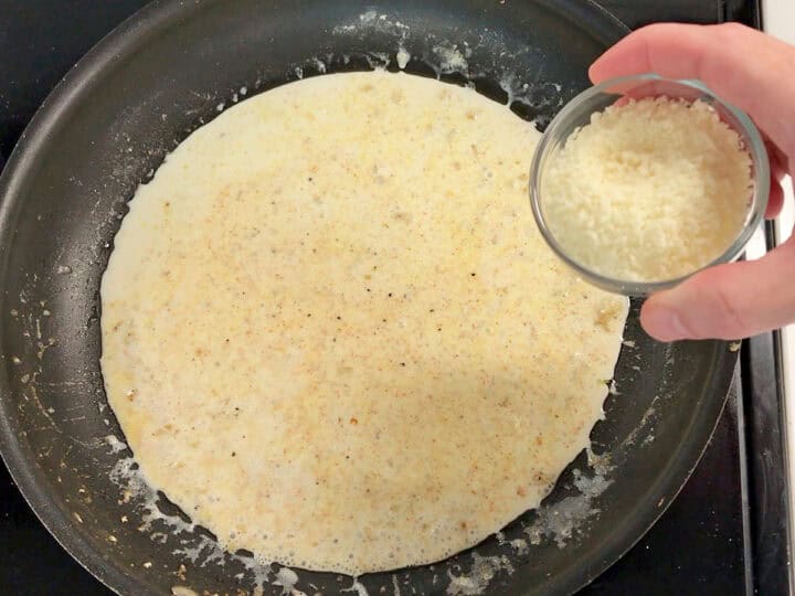 Adding parmesan to the skillet.