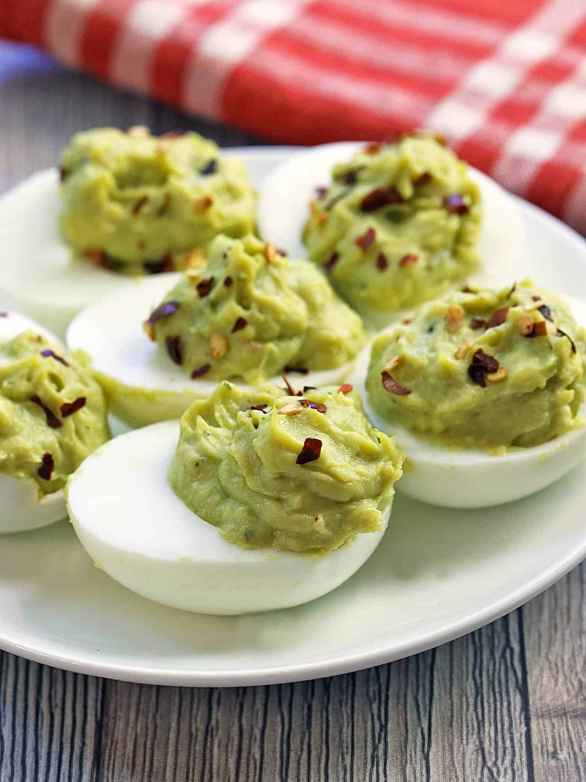Avocado deviled eggs are served on a white plate.