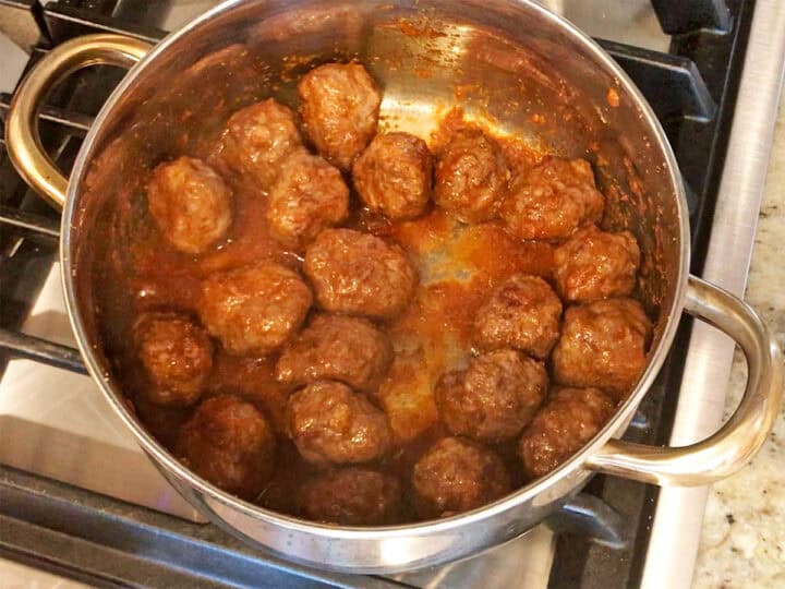 Coating the meatballs in the sauce.