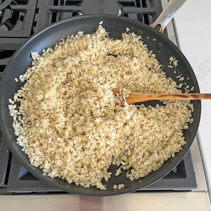 Cooking the cauliflower in a skillet.
