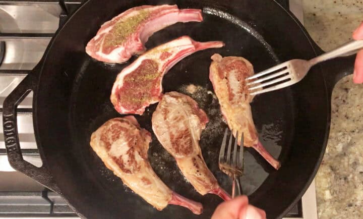 Cooking lamb chops in a cast-iron skillet.